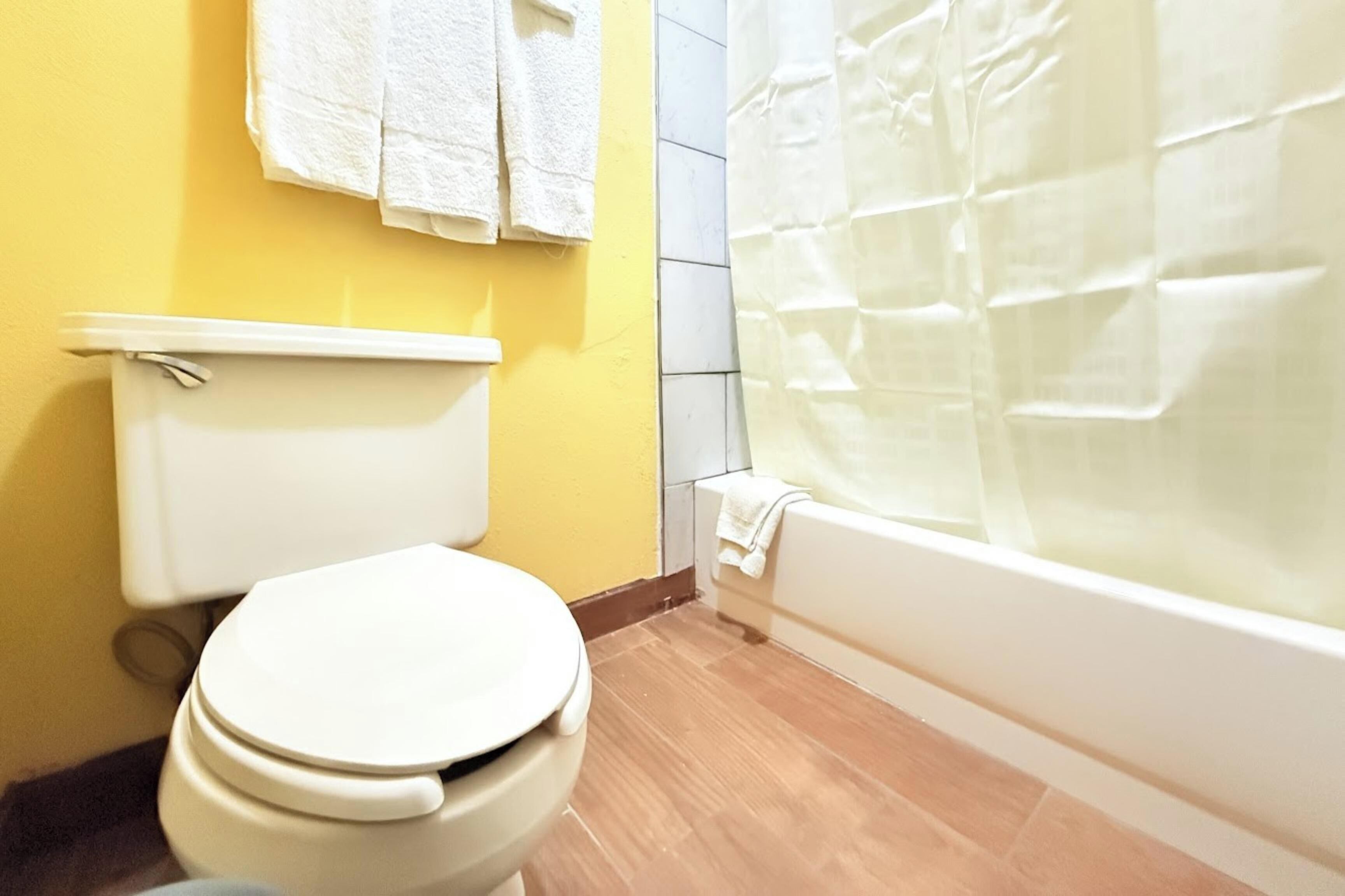 A bathroom with a toilet, a bathtub, and a shower curtain.