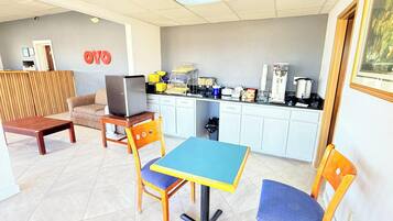 Una habitación pequeña y luminosa con kitchenette, un sofá, una mesa y un televisor.
