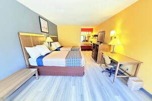 Habitación de hotel con cama, escritorio, silla, televisión y una pequeña kitchenette.