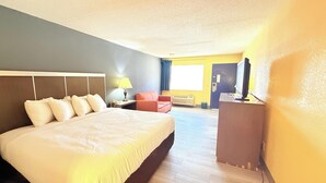 A hotel room with a large bed, a desk with a computer, a chair, and a TV. - OYO Hotel Williamston (Williamston)
