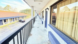 A corridor with a balcony, a parking area, and a building with large windows. - OYO Hotel Williamston (Williamston)