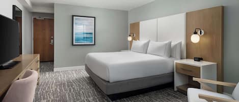 A hotel room with a bed, bedside tables, a desk, a chair, a television, and a framed picture on the wall.