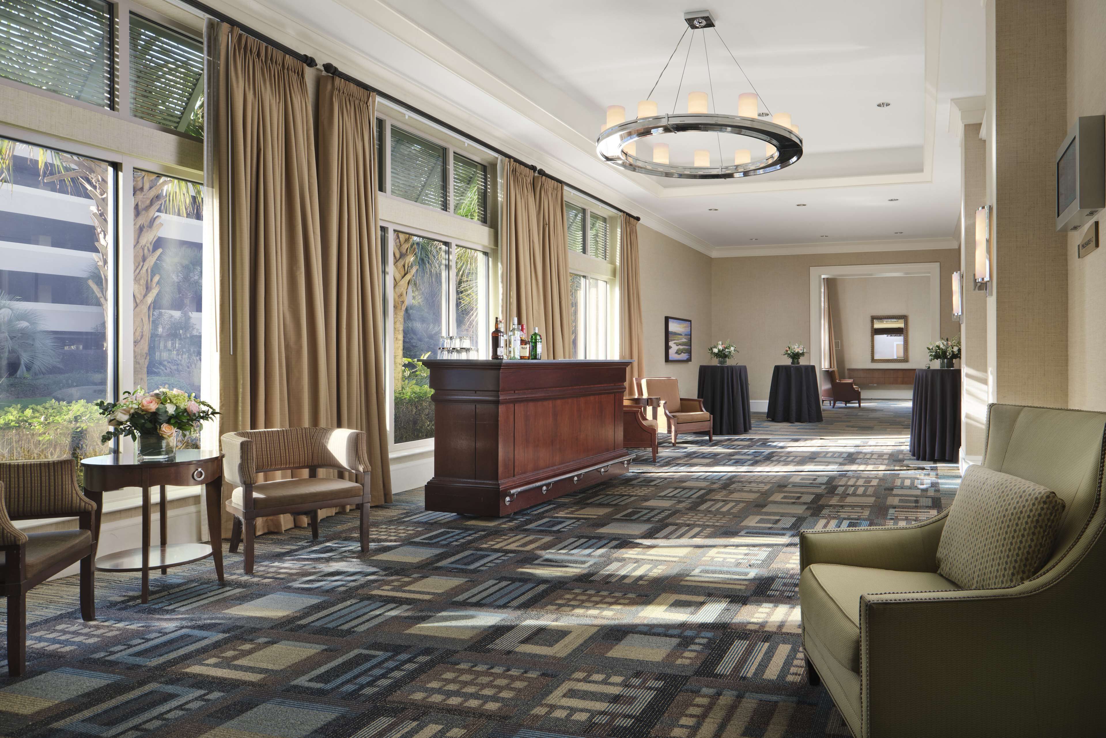 A spacious hotel lobby with a patterned carpet, a reception desk, and seating areas.