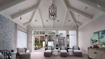 A spacious living area with a high ceiling, large windows, and a view of the outdoors.