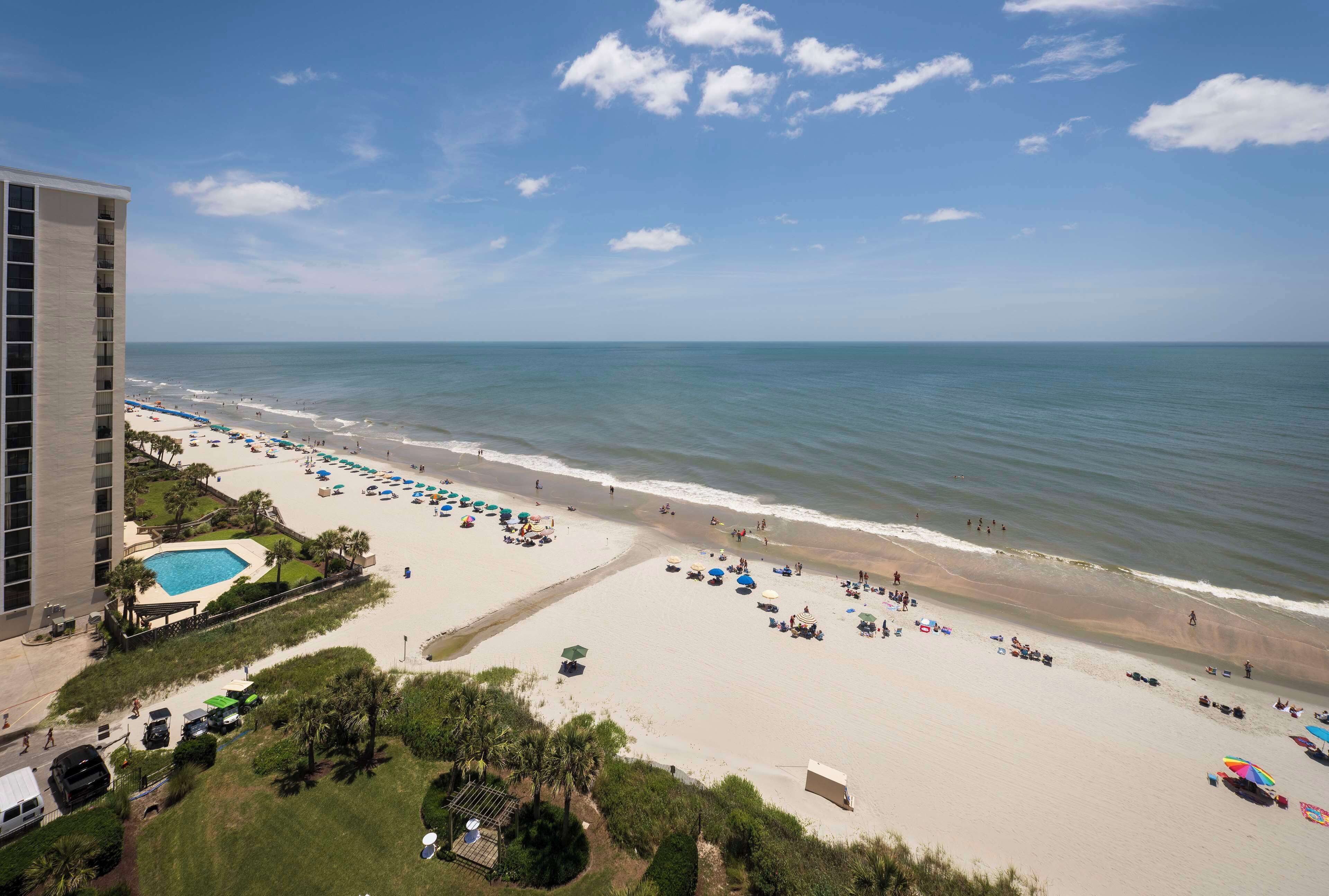 Una playa con piscina, sombrillas y un edificio de hotel.