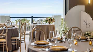 A dining area with round tables, chairs, and a view of the sea.