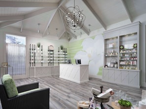 A spacious room with a high ceiling, a central island with shelves, and a large floral mural.