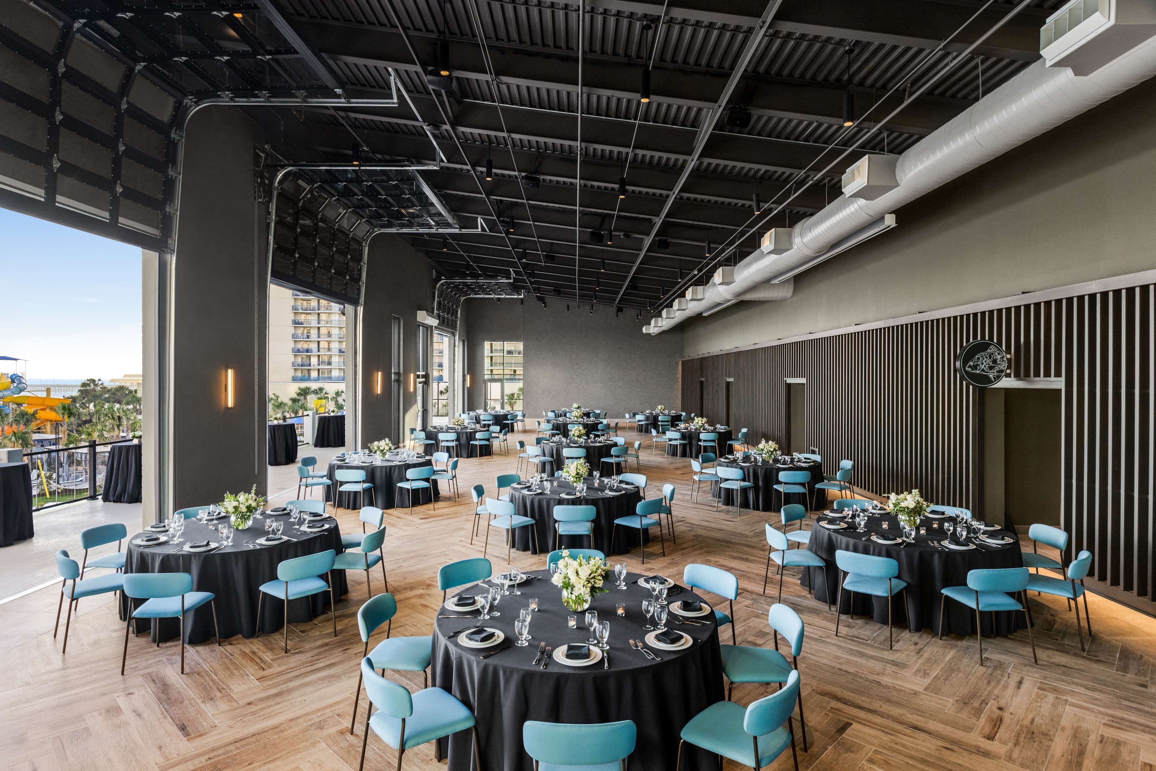 A spacious indoor dining area with multiple round tables, each set with chairs and table settings.