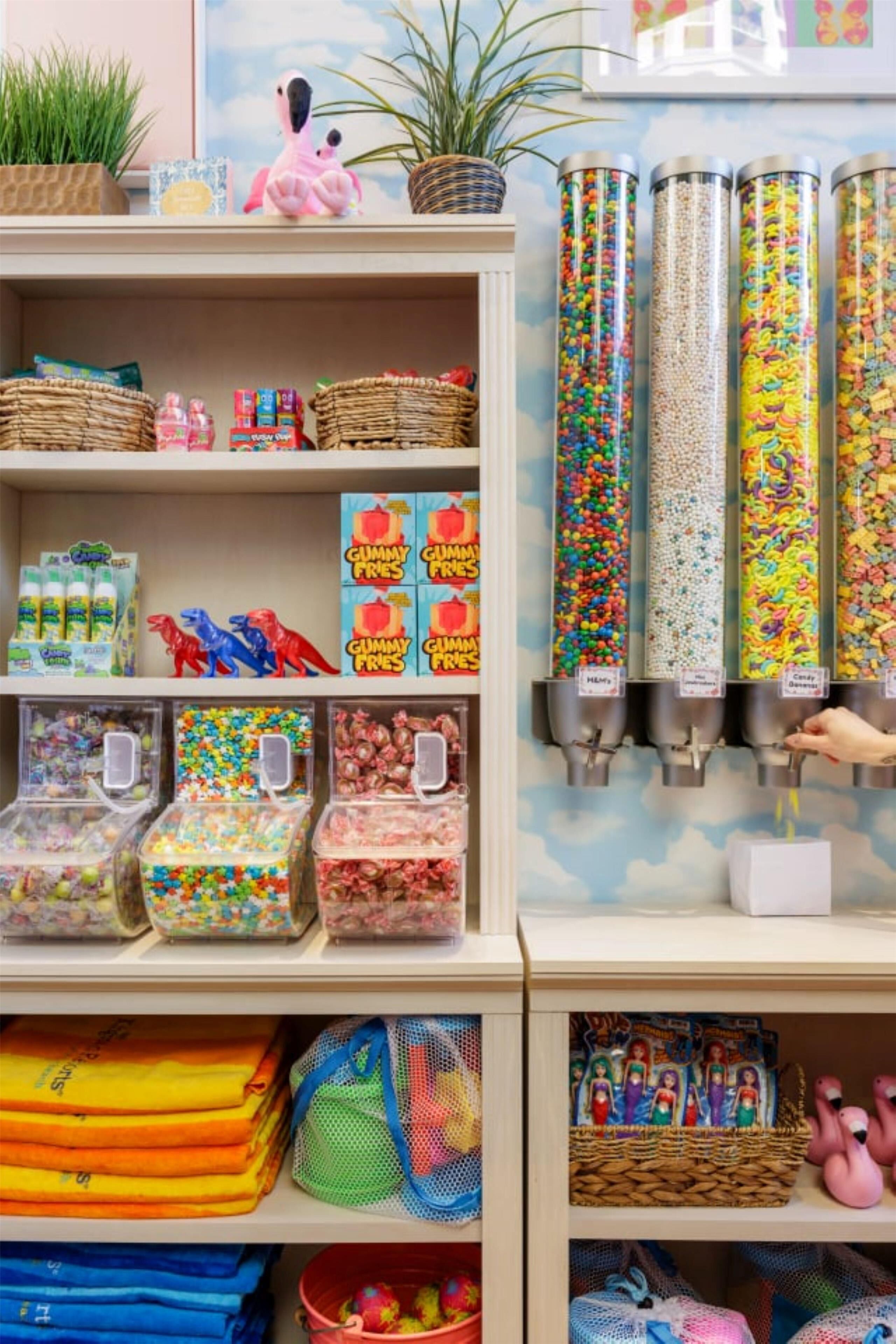 A candy store with various colorful candies and a hand reaching for a candy dispenser.