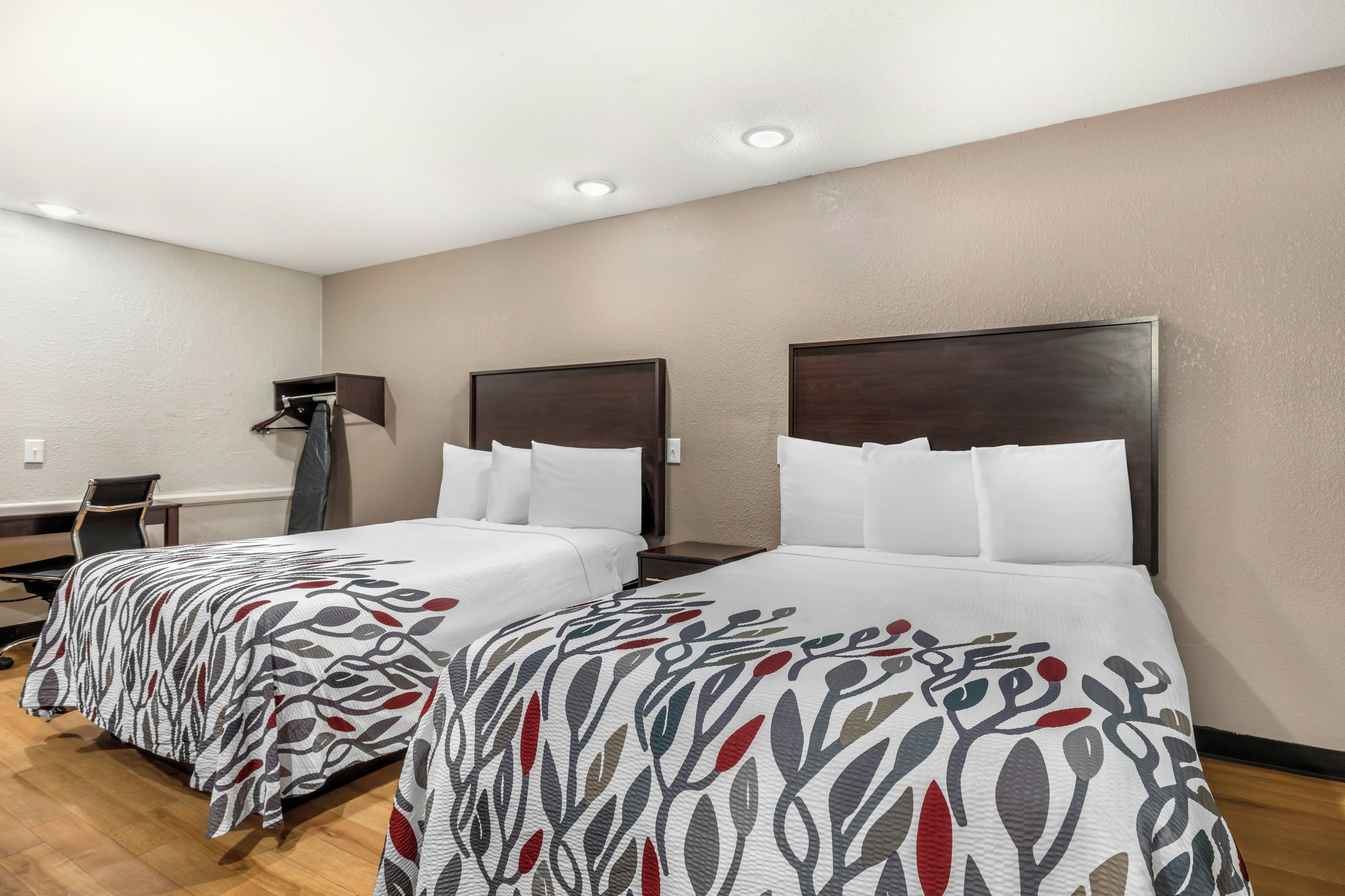 Habitación de hotel con dos camas, un escritorio y una silla.