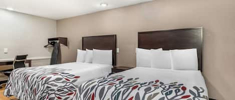A hotel room with two beds, a desk, and a chair.