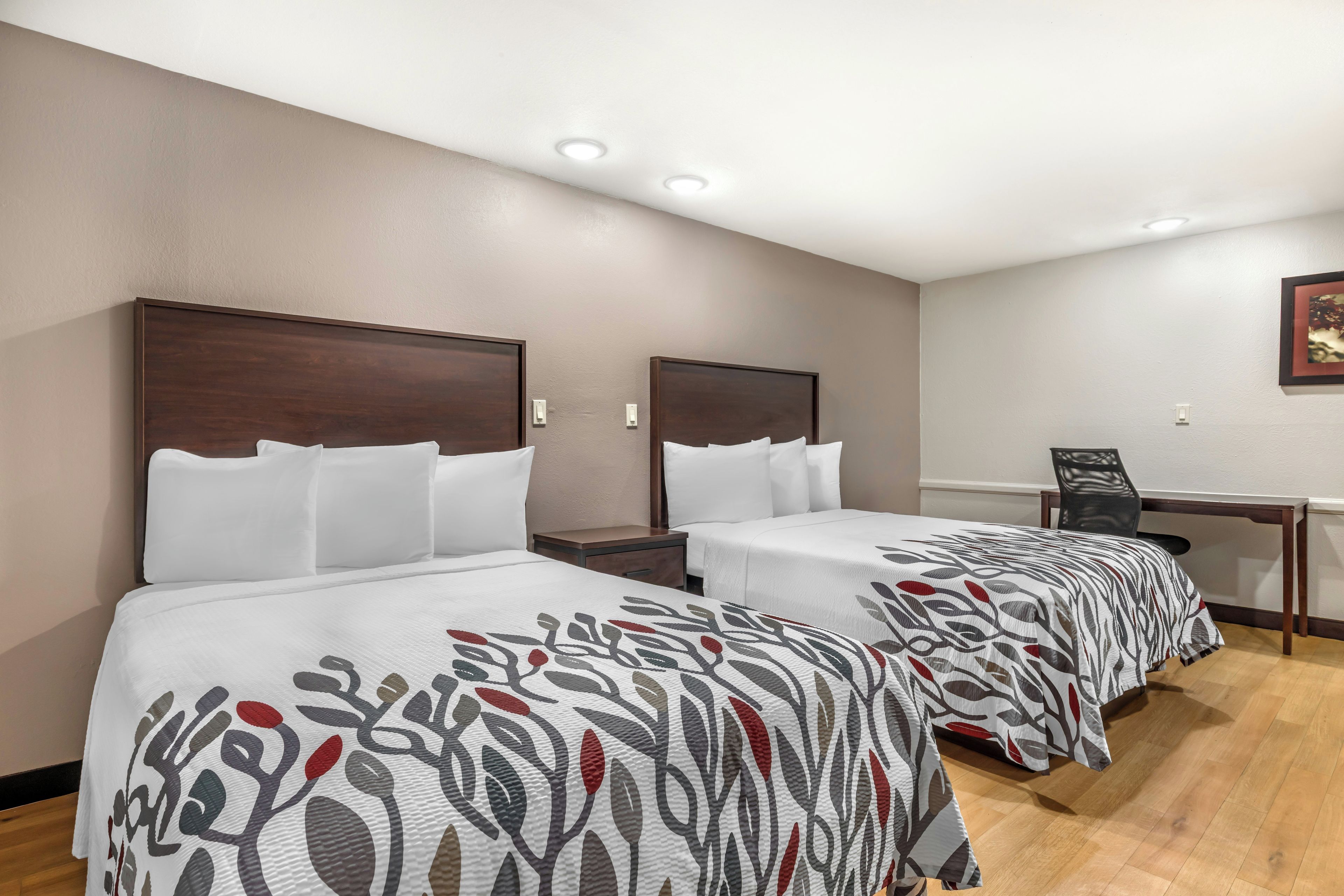 Ein Hotelzimmer mit zwei Betten, einem Schreibtisch und einem Stuhl.