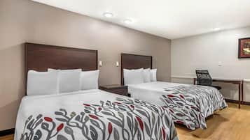Ein Hotelzimmer mit zwei Betten, einem Schreibtisch und einem Stuhl.