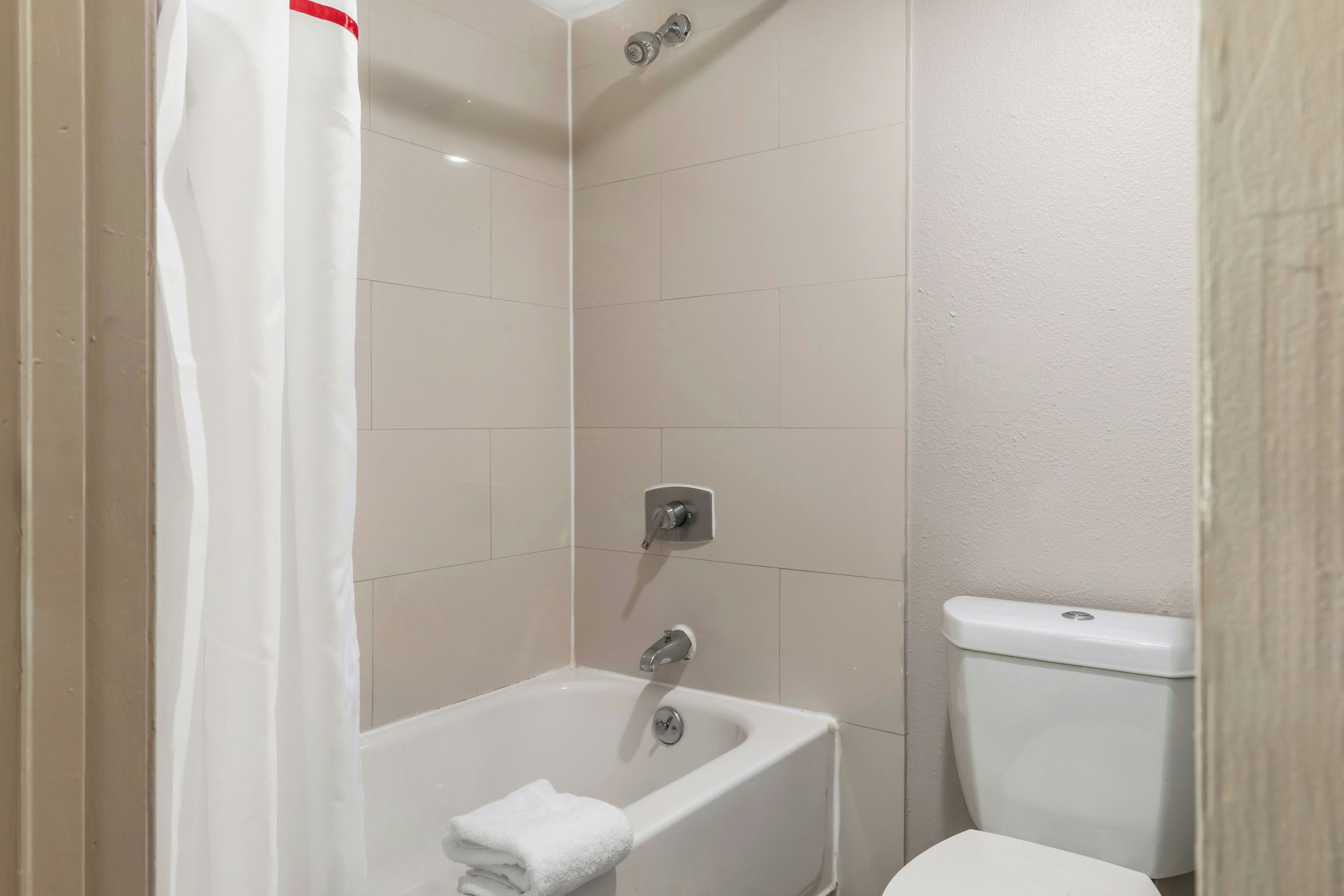 A bathroom with a bathtub, a toilet, and a shower curtain.