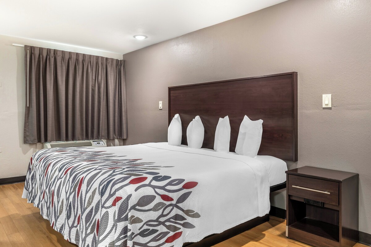 Une chambre d’hôtel avec un grand lit, une table de chevet et une fenêtre avec des rideaux.