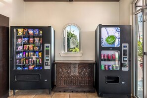 Two vending machines with snacks and drinks, a window with a view, and a decorative wooden bench. - Red Roof Inn North Dallas - Park Central (Dallas)