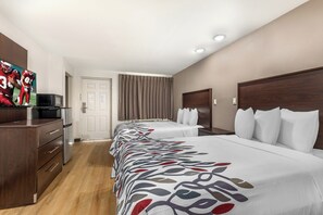 A hotel room with a bed, a desk, a television, and a door. - Red Roof Inn North Dallas - Park Central (Dallas)