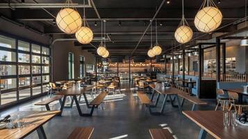 Un intérieur de restaurant moderne avec des tables en bois et des luminaires sphériques suspendus.
