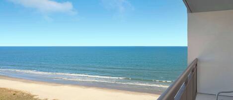 Un balcon avec vue sur la plage et l’océan.