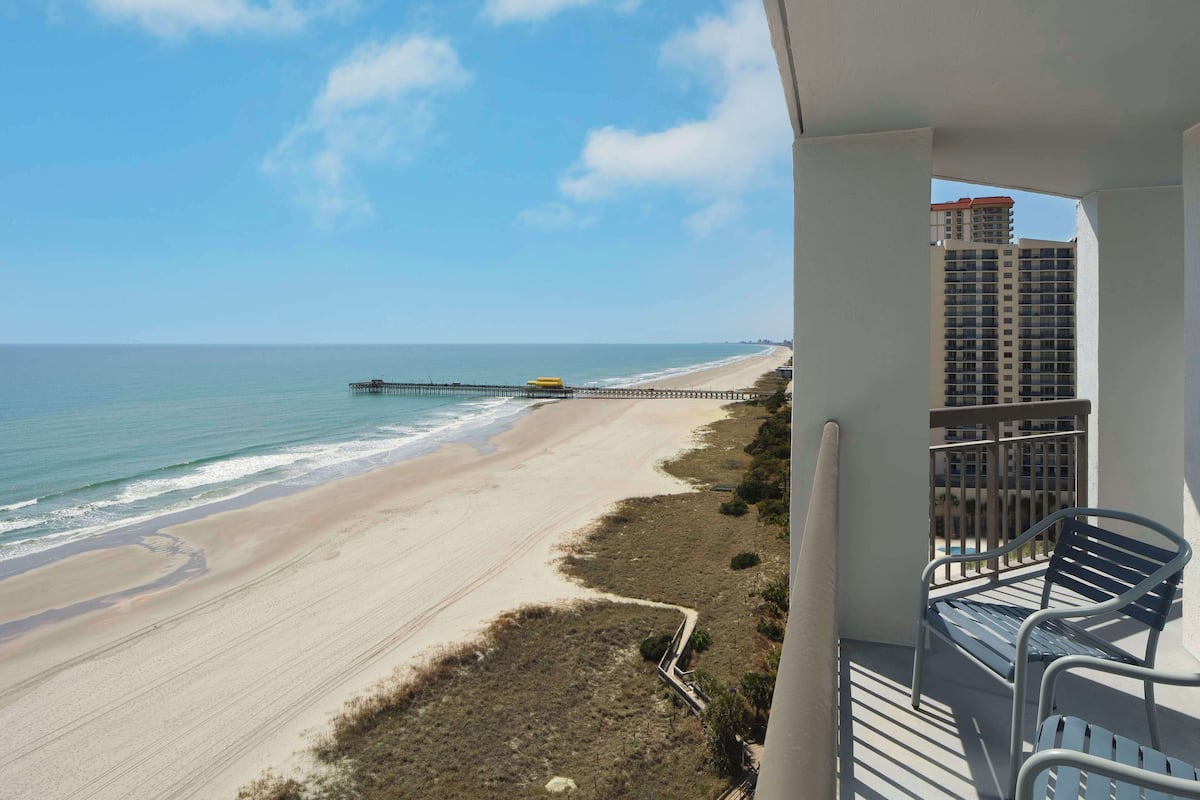 A balcony with a view of a beach and a pier.