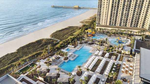 Un resort con una piscina grande, tumbonas y vista a la playa.