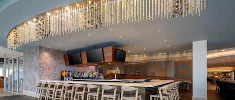 A modern bar area with a curved ceiling, a long bar counter, and multiple seating arrangements.