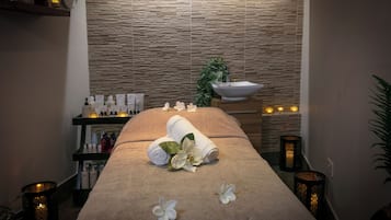 Experience a serene spa room with a massage table, toiletries, and fresh flowers.