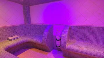 Une salle de spa dotée d’un espace détente aux lignes courbes et d’un petit lavabo.