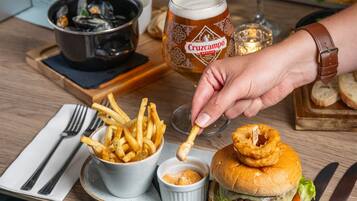 En måltid bestående av en hamburgare, pommes frites och ett glas öl, serverat på ett bricka.