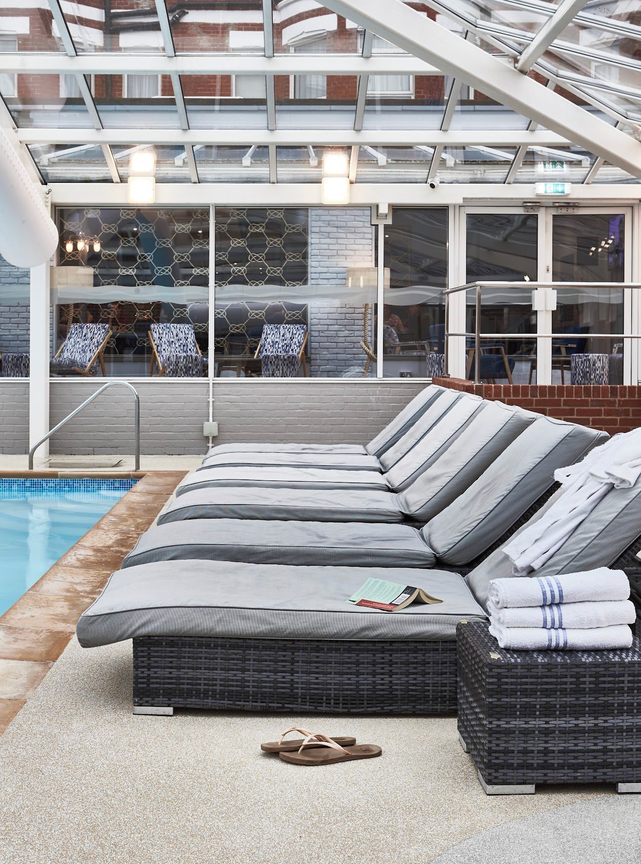 Un área de descanso junto a la piscina con asientos, una piscina y vistas al exterior.