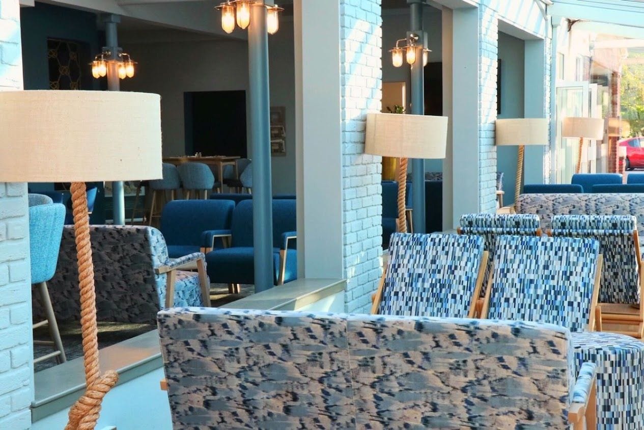 A seating area with patterned chairs, a rope barrier, and hanging lamps.