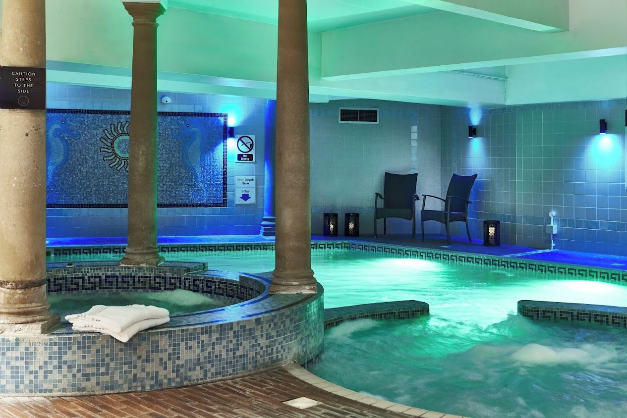 A hot tub area with a mosaic wall, a caution sign, and a chair.