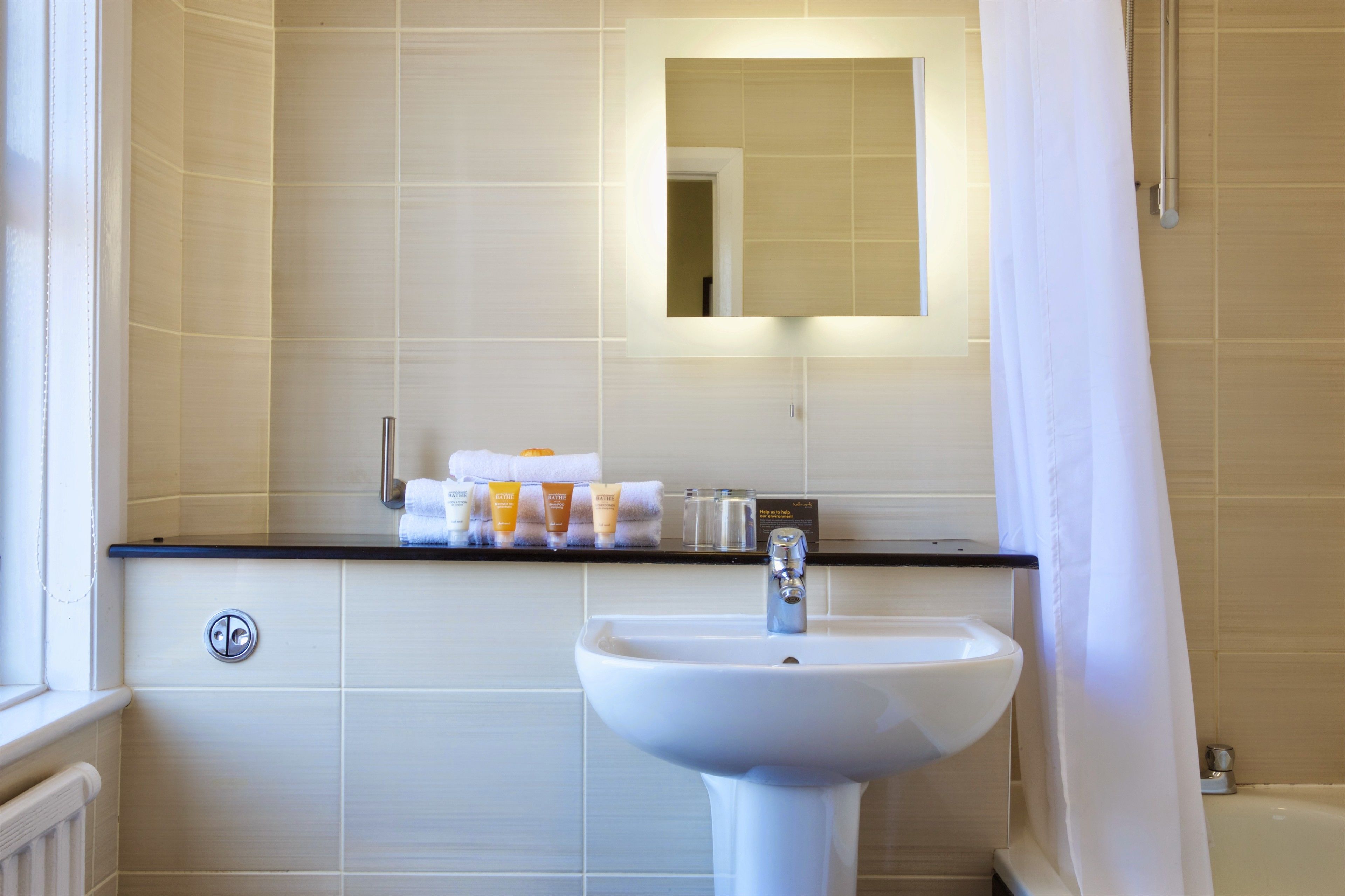 A bathroom with a white sink, a mirror, and a shelf with toiletries.