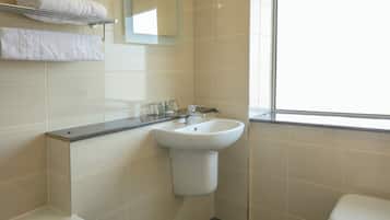 A bathroom with a white sink, a mirror, and a window.