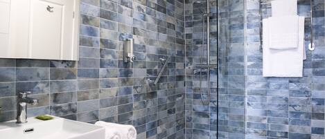 Un bagno moderno con cabina doccia in vetro, lavabo bianco e parete rivestita di piastrelle.