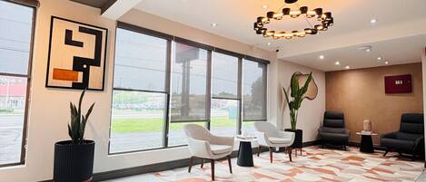 Un hall d’entrée spacieux, doté de grandes fenêtres, d’un lustre moderne et de plusieurs coins salon.