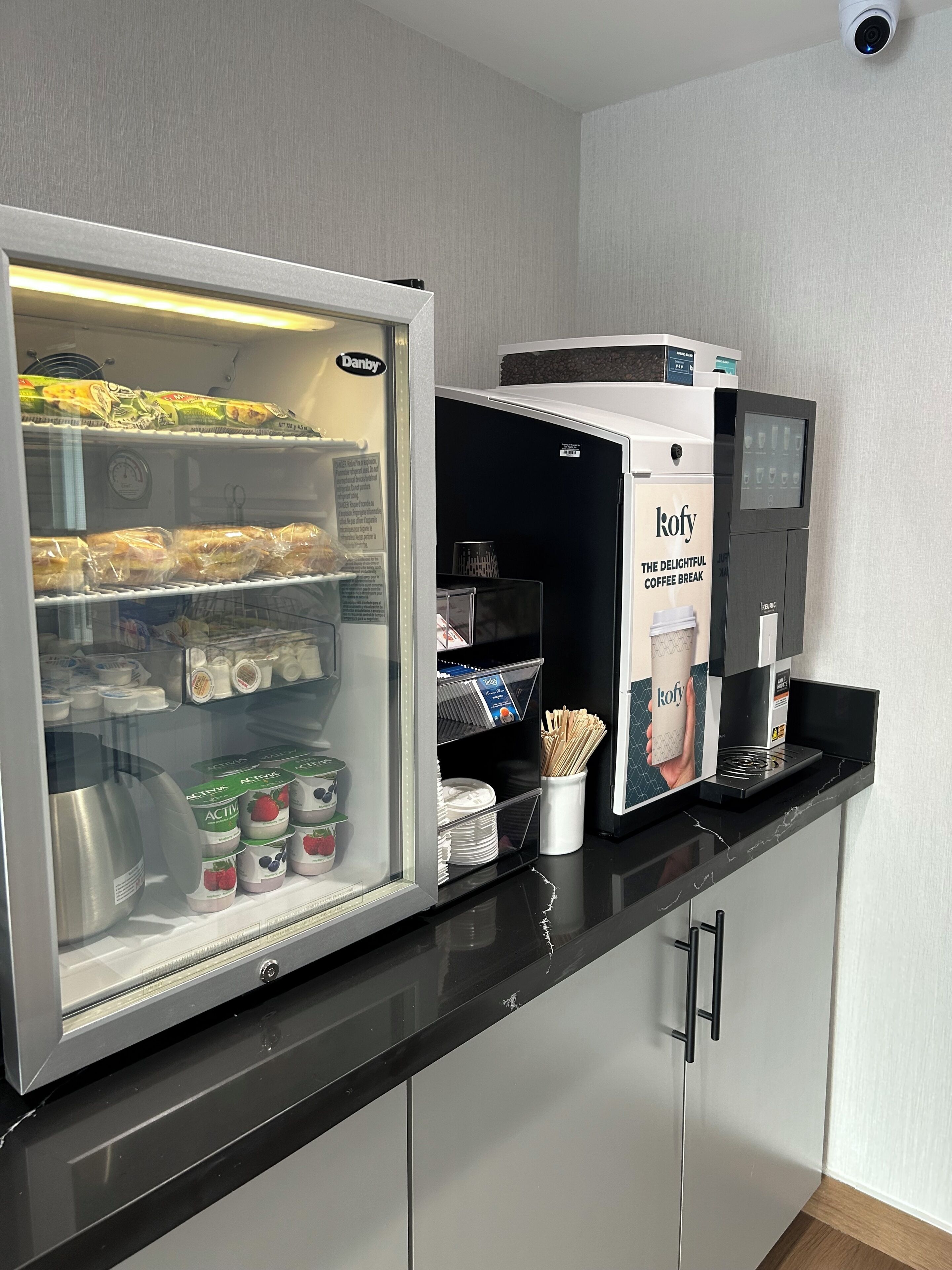 A refrigerator stocked with food items and a coffee machine labeled 'Kofy The Delightful Coffee Break'.