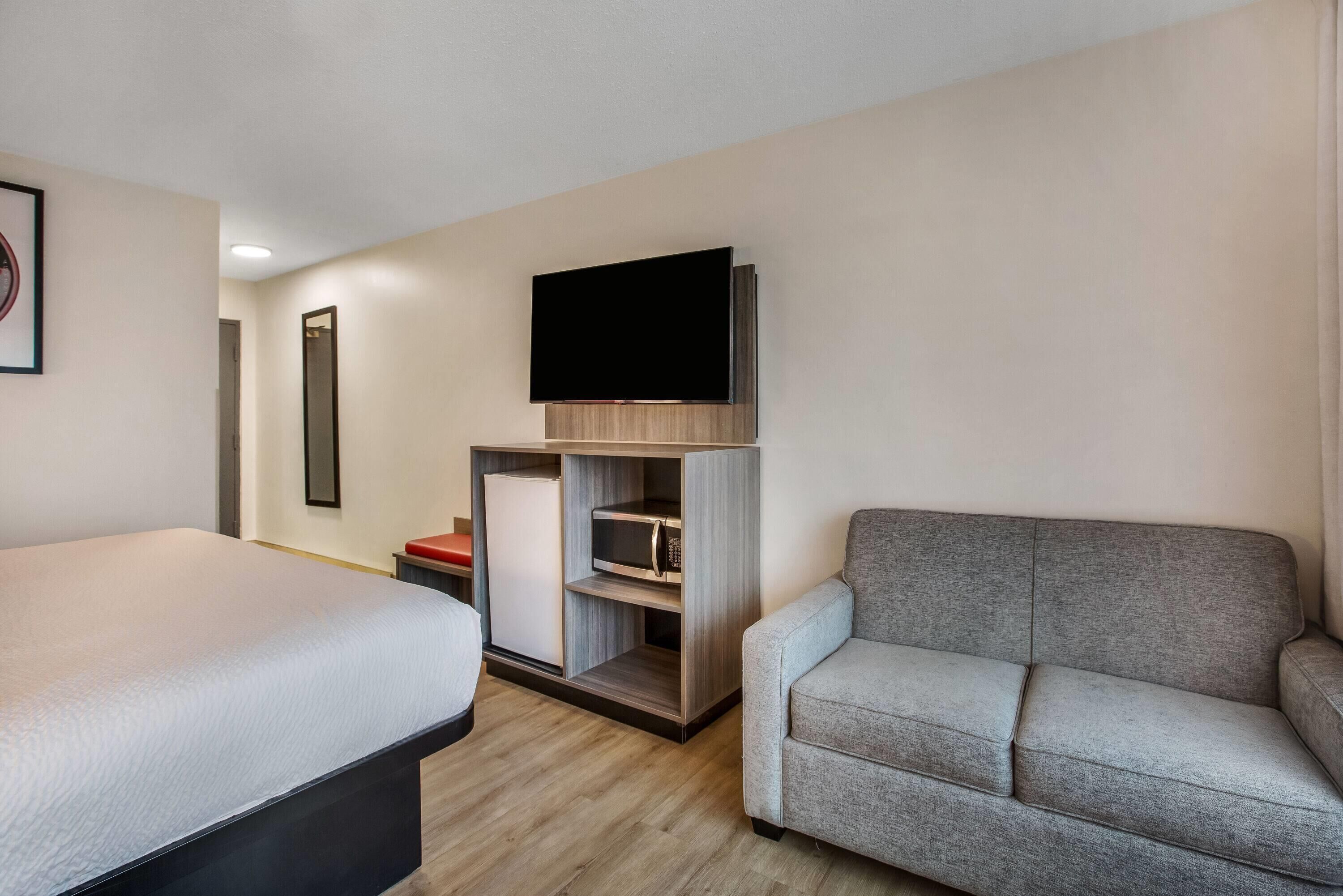 Une chambre d’hôtel équipée d’un lit, d’un canapé, d’une télévision à écran plat, d’un mini-réfrigérateur et d’un four à micro-ondes.