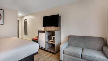 Ein Hotelzimmer mit einem Bett, einem Schlafsofa, einem Flachbildfernseher, einer Minikühlschrank und einer Mikrowelle.