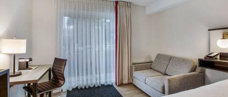 Una habitación de hotel con escritorio, silla, sofá y cama.