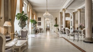 A grand lobby with high ceilings, ornate columns, and a central chandelier. - Grand Hotel Rimini (Rimini)