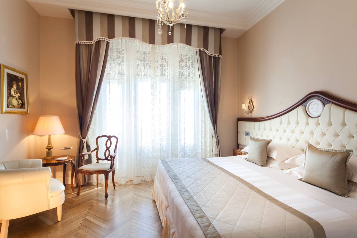 Een hotelkamer met een groot bed, een stoel, een lamp en een schilderij aan de muur.