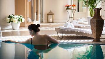 Relax by the serene pool surrounded by a lounge area with comfortable seating and a beautiful floral arrangement.