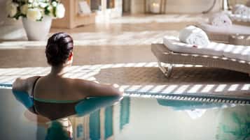 A woman in a bikini sitting by a pool with lounge chairs and towels in the background.