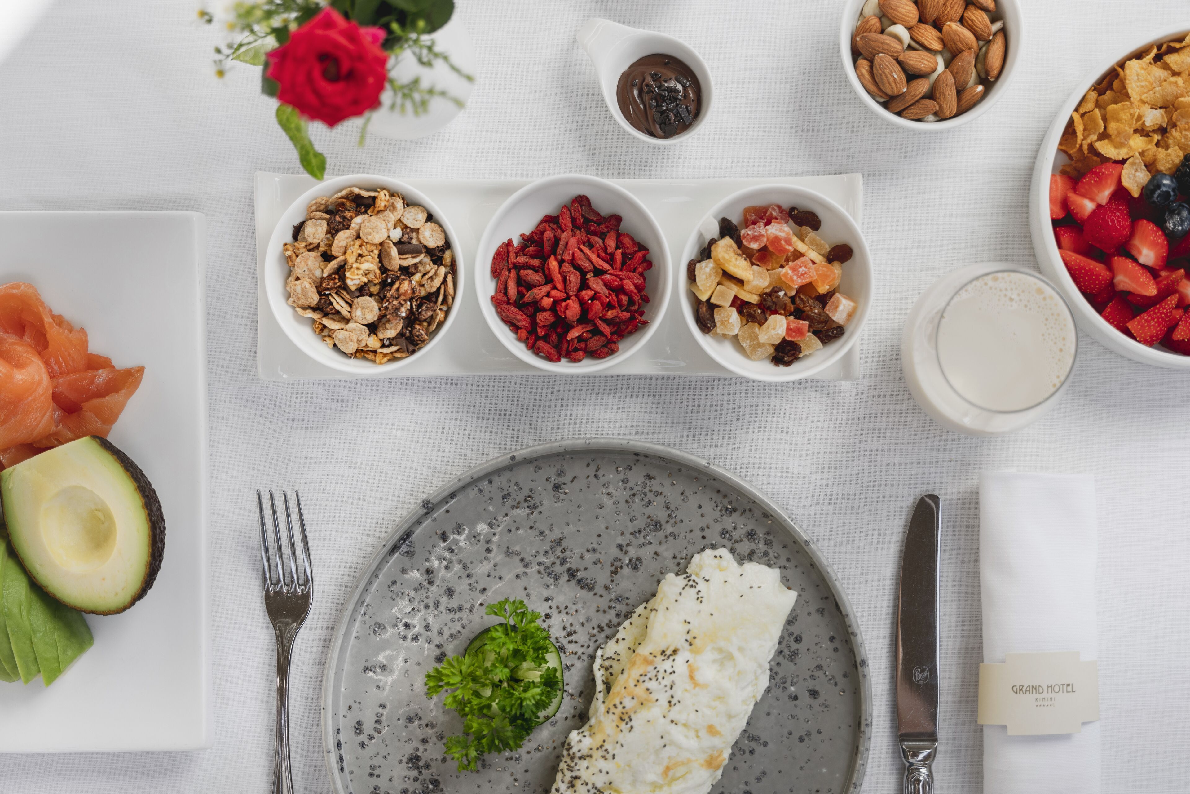 A breakfast setting with various food items, including salmon, avocado, and a plate with an egg and greens.