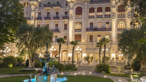 A grand hotel with a well-maintained garden, a fountain, and a paved walkway leading to the entrance. - Grand Hotel Rimini (Rimini)