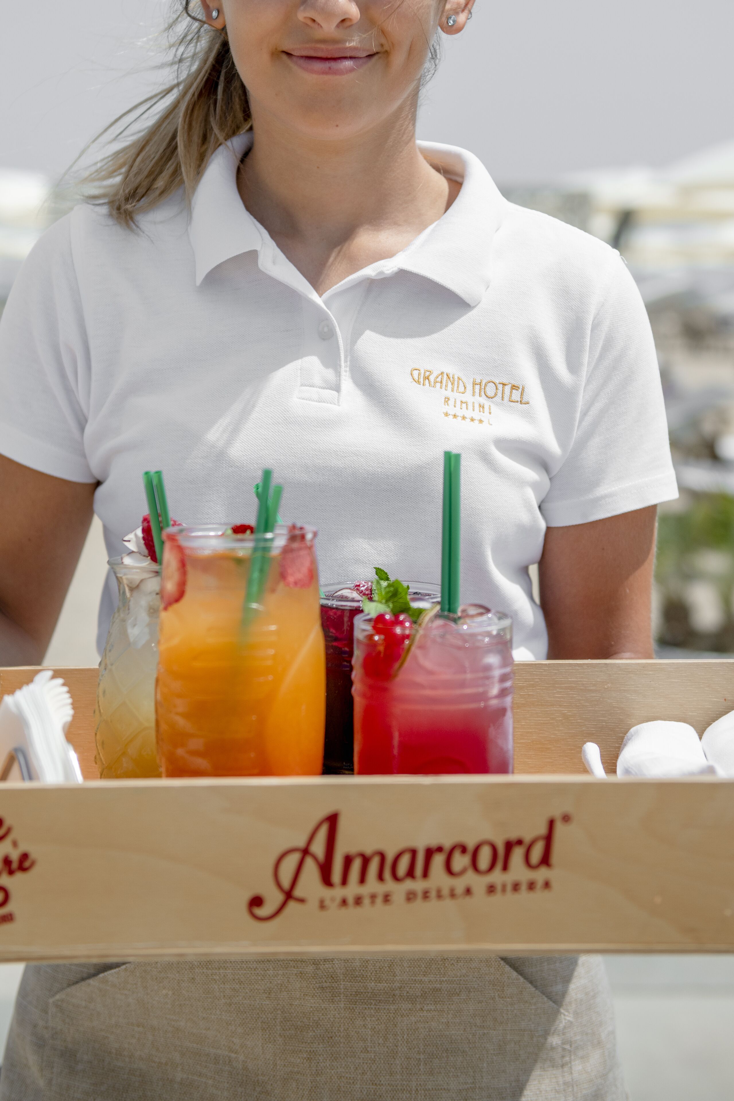A person holding a tray with drinks and a box labeled "Amarcord."