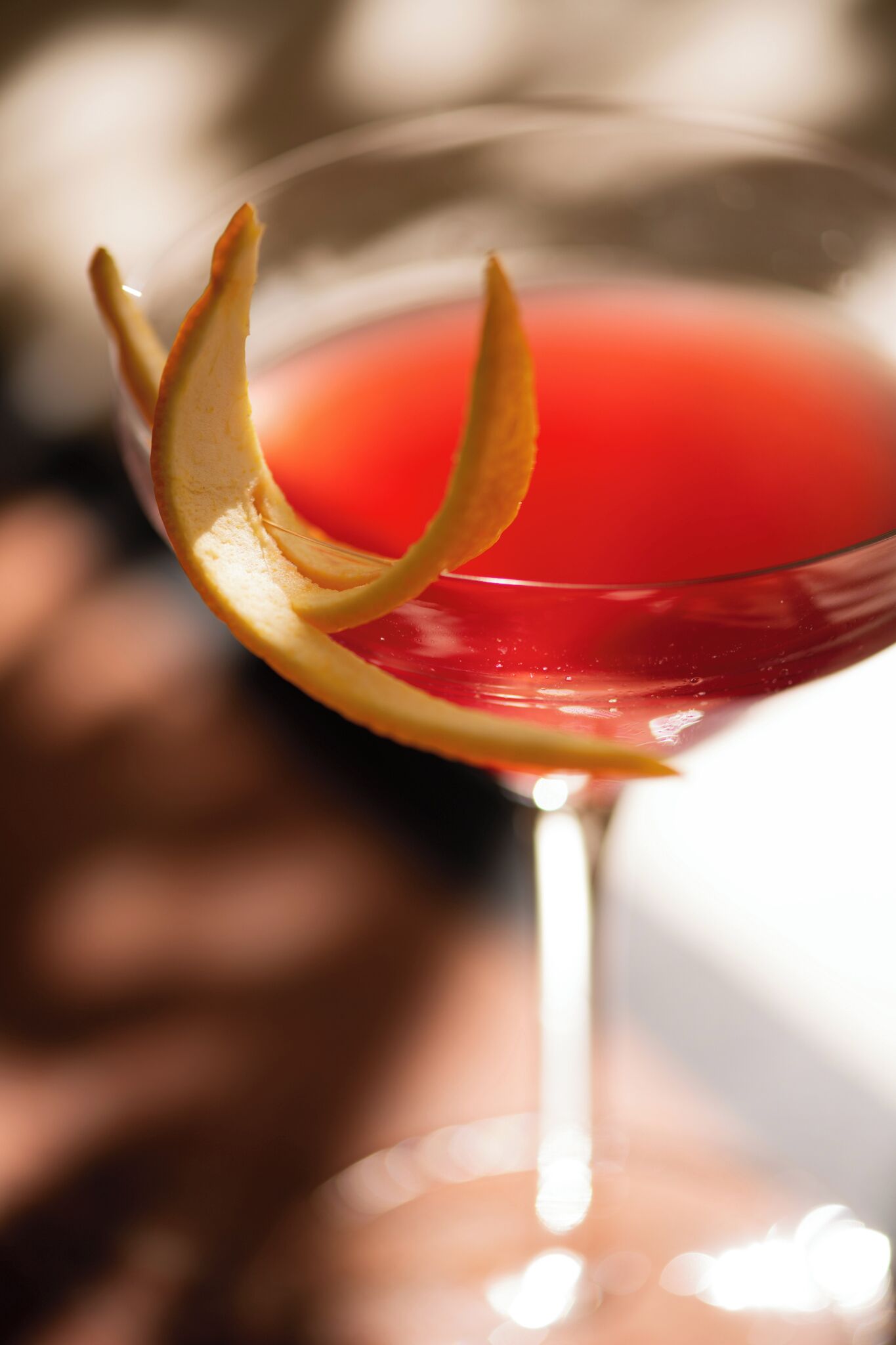 Un primo piano di un bicchiere da cocktail con una bevanda rossa e una guarnizione di frutta decorativa.