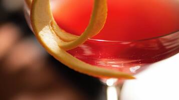 Un primo piano di un bicchiere da cocktail con una bevanda rossa e una guarnizione di frutta decorativa.