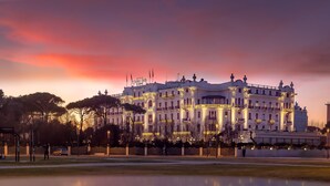 A grand hotel with classical architecture, multiple balconies, and a well-lit facade.